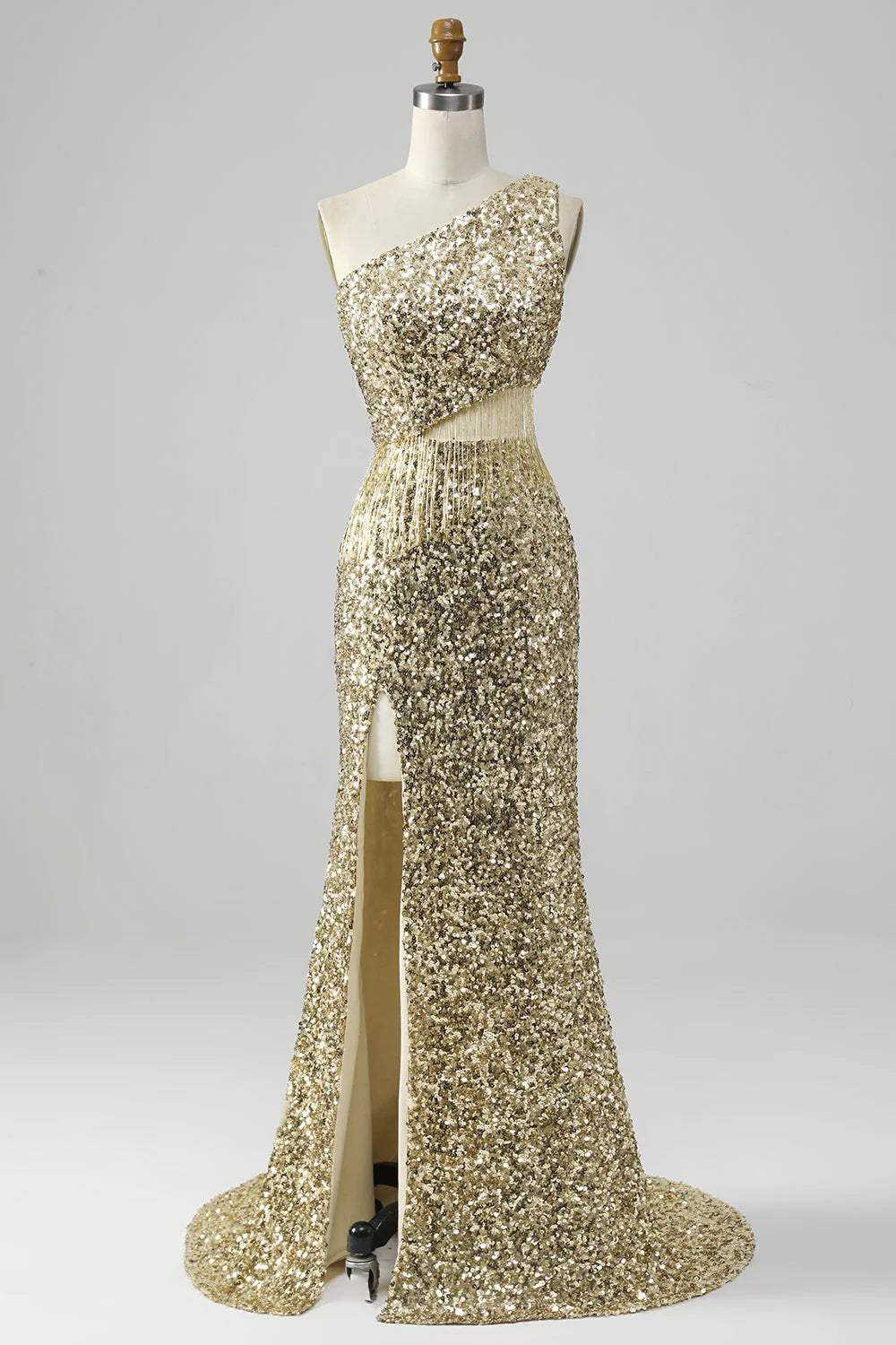 Model wearing a golden one-shoulder sequin prom dress with fringe and a high slit.