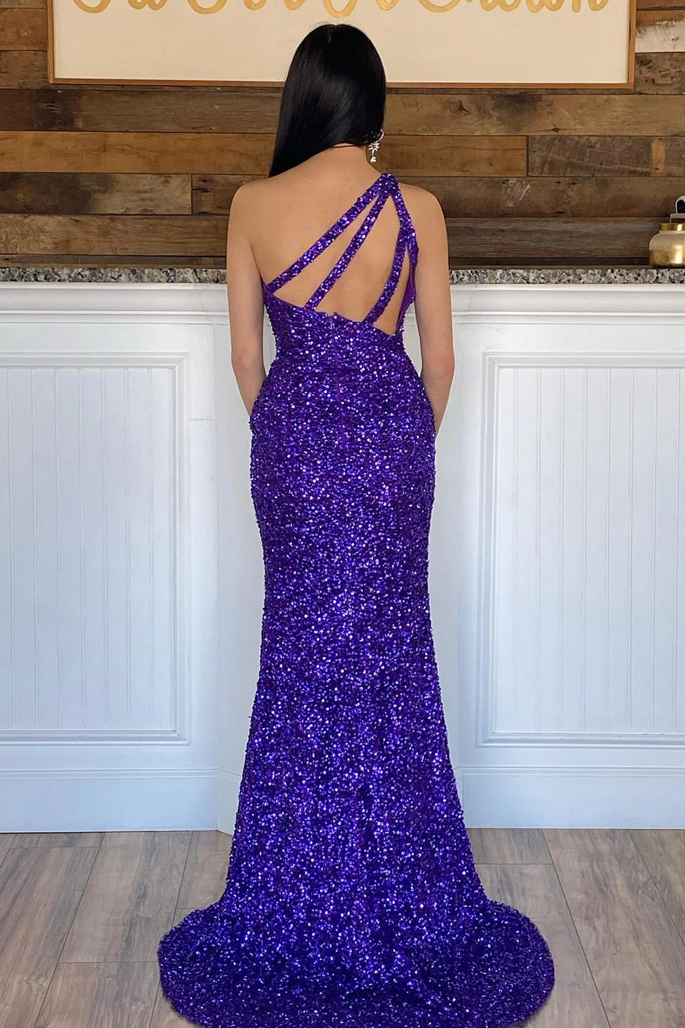 Back view of a model in a long purple sequin one-shoulder evening gown.