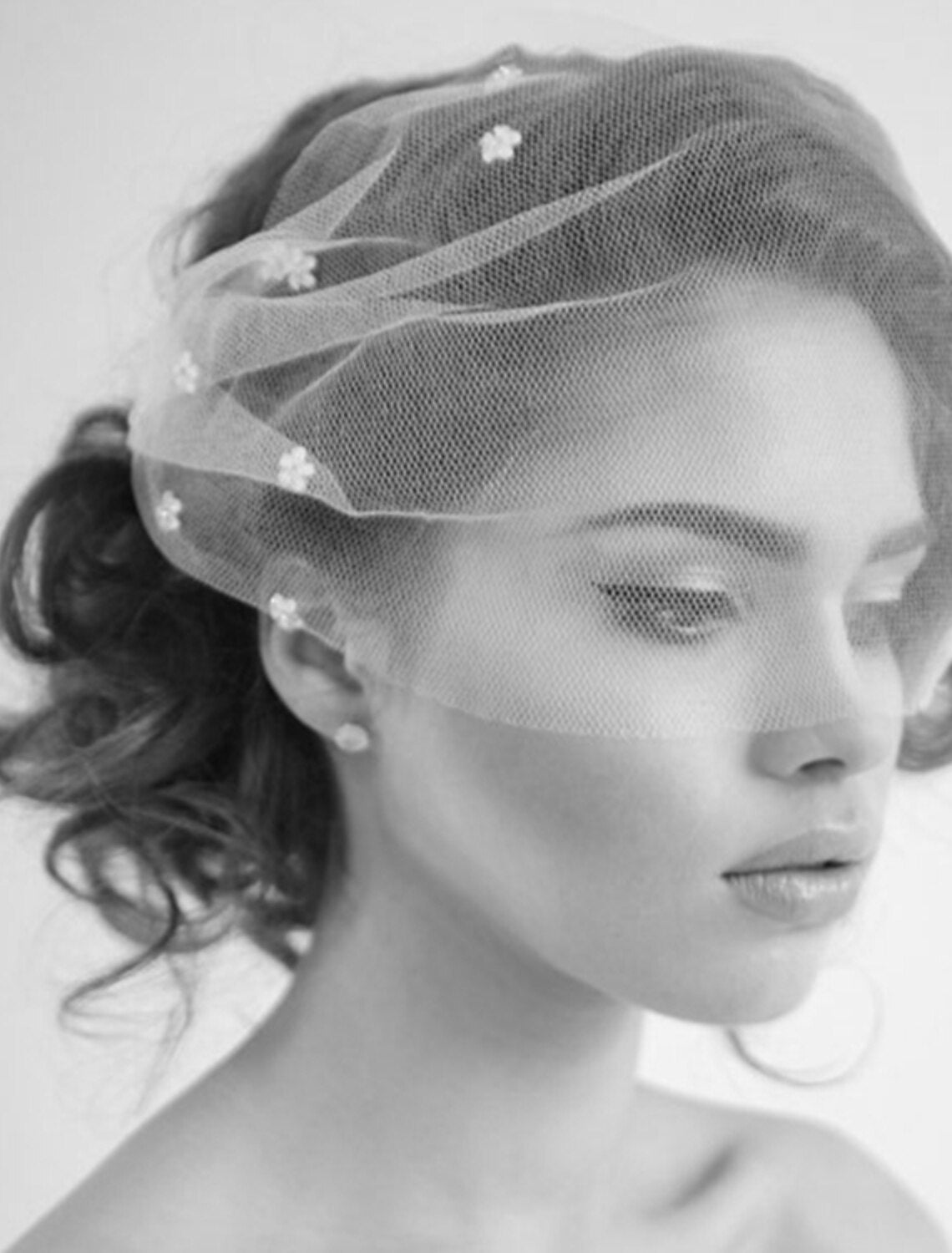 Front view of a blusher wedding veil with a bride's face partially obscured, highlighting the veil's design.