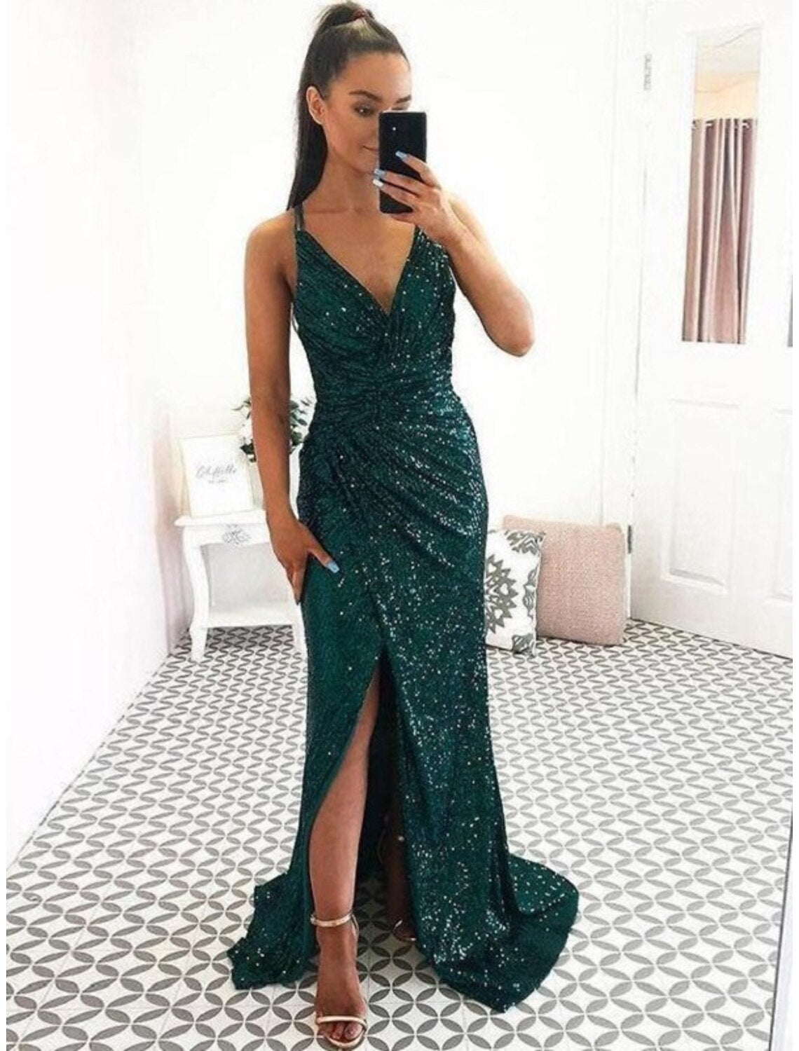Woman wearing a dazzling sequined mermaid prom dress with a V-neck, backless design, and a high slit.