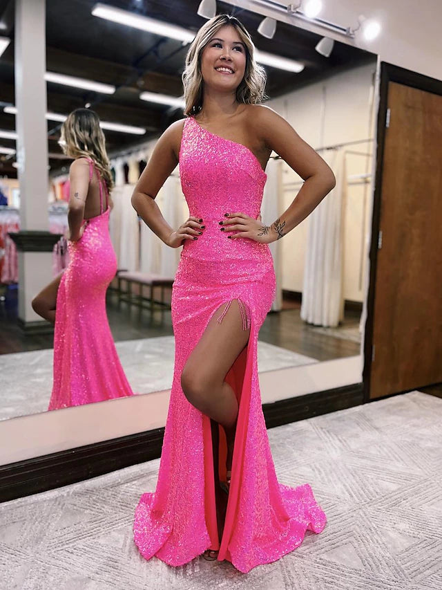 Model wearing a dazzling sequined one-shoulder mermaid prom dress with a high slit.