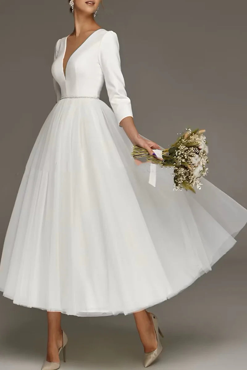 Model wearing a white 1940s 1950s tea length wedding dress with 3/4 sleeves and V-neck.