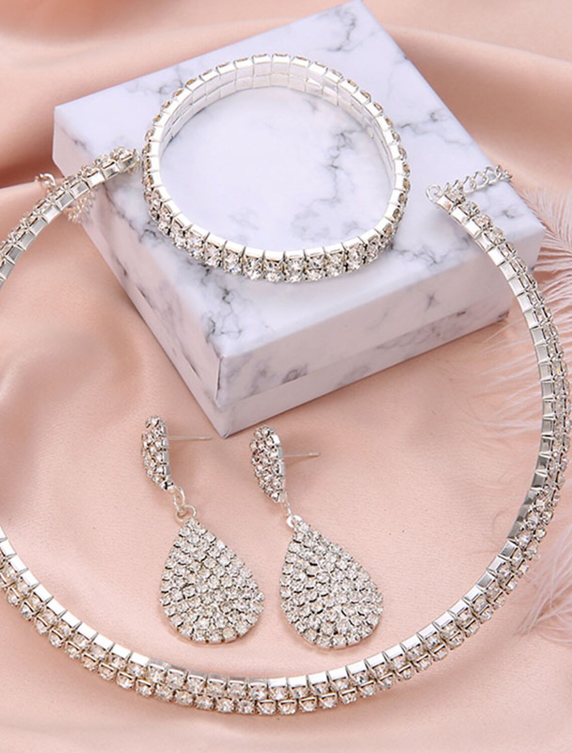 Woman wearing an elegant silver-toned bridal jewelry set, including a necklace with a pendant, drop earrings, a bracelet.
