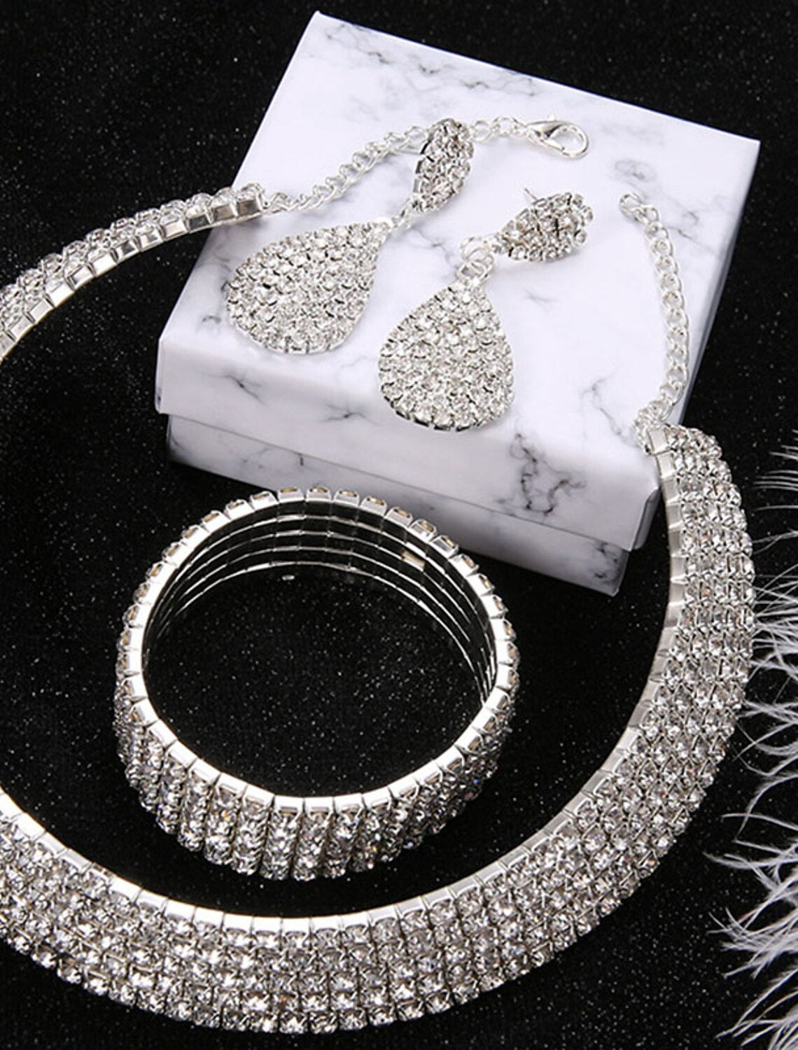 Close-up of an elegant 4-piece bridal jewelry set featuring a necklace, bracelet, earrings, and chrome rings.