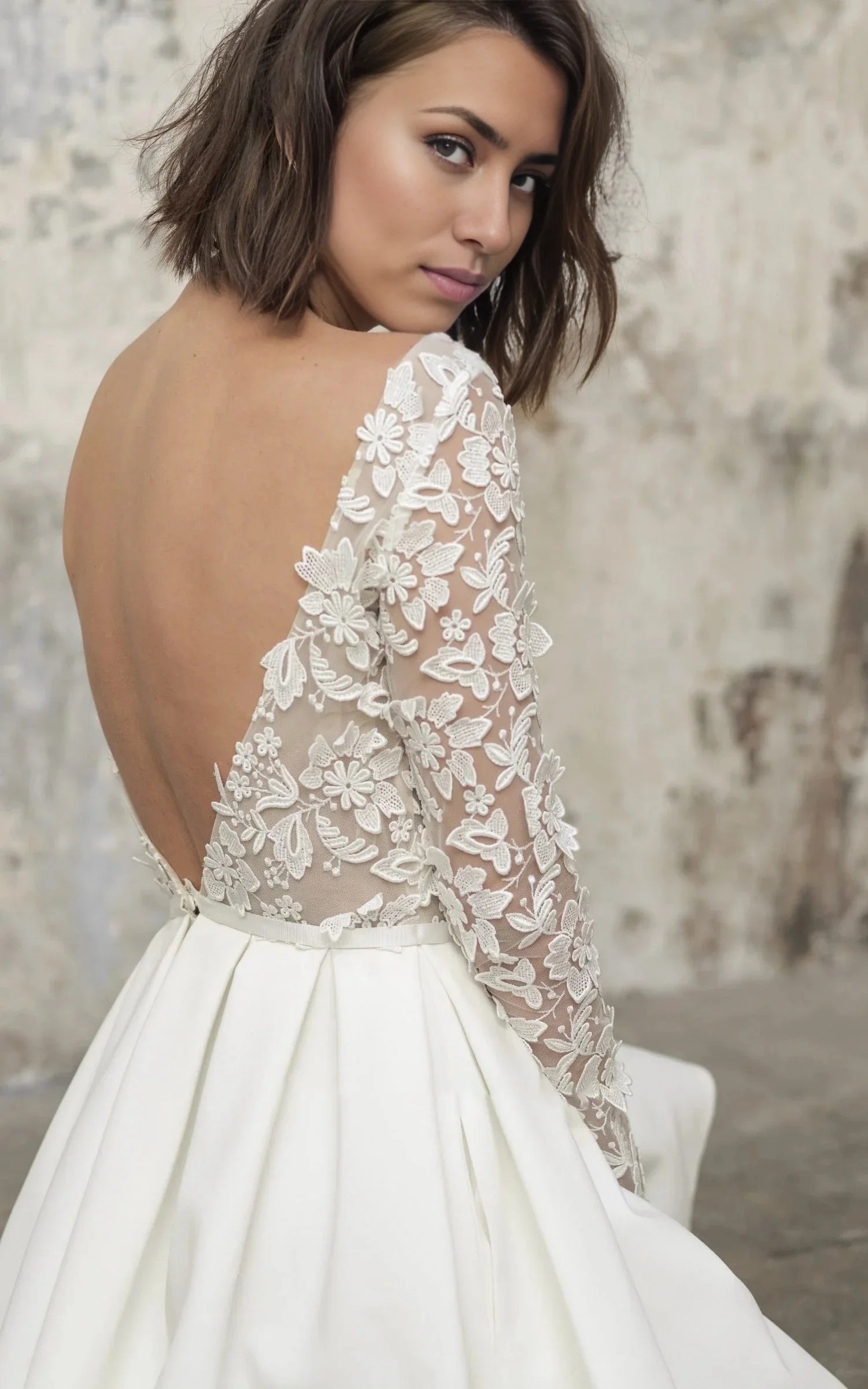 Back view of a satin lace A-line wedding dress with long sleeves.