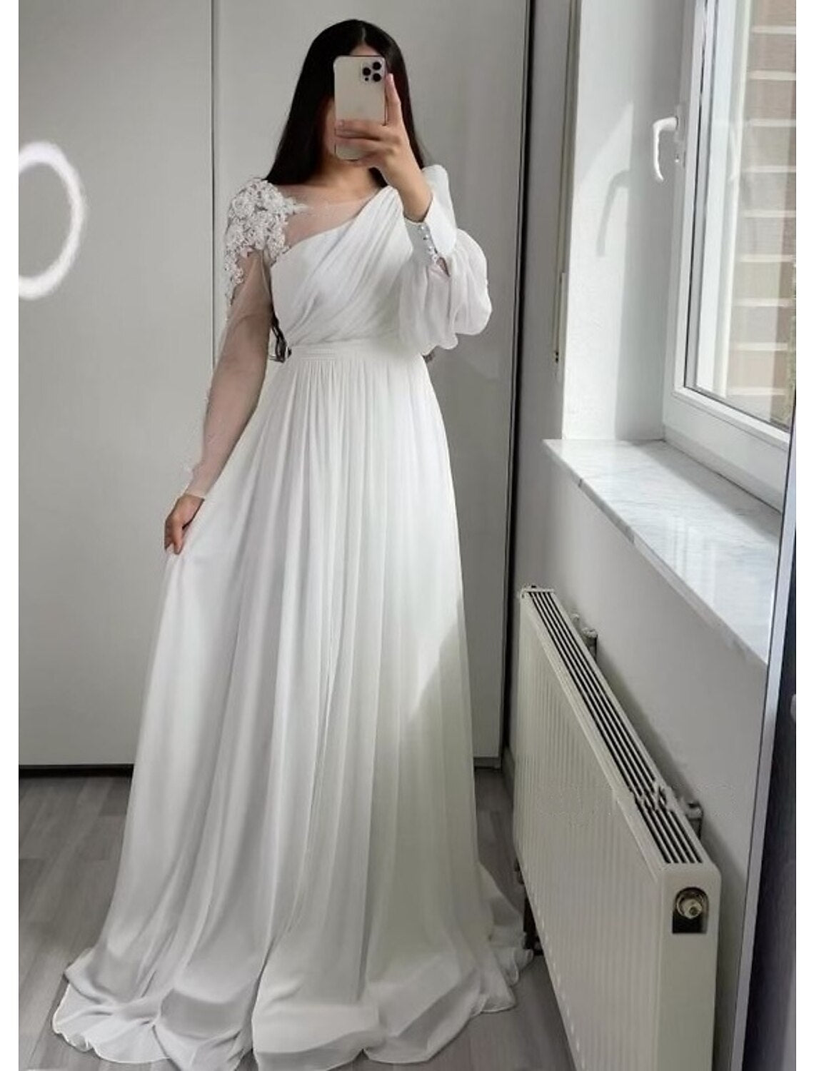 White A-Line wedding dress with boat neck, long sleeves, pleats, and appliques.