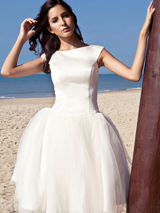Model wearing the knee-length white wedding dress, showcasing its graceful movement.