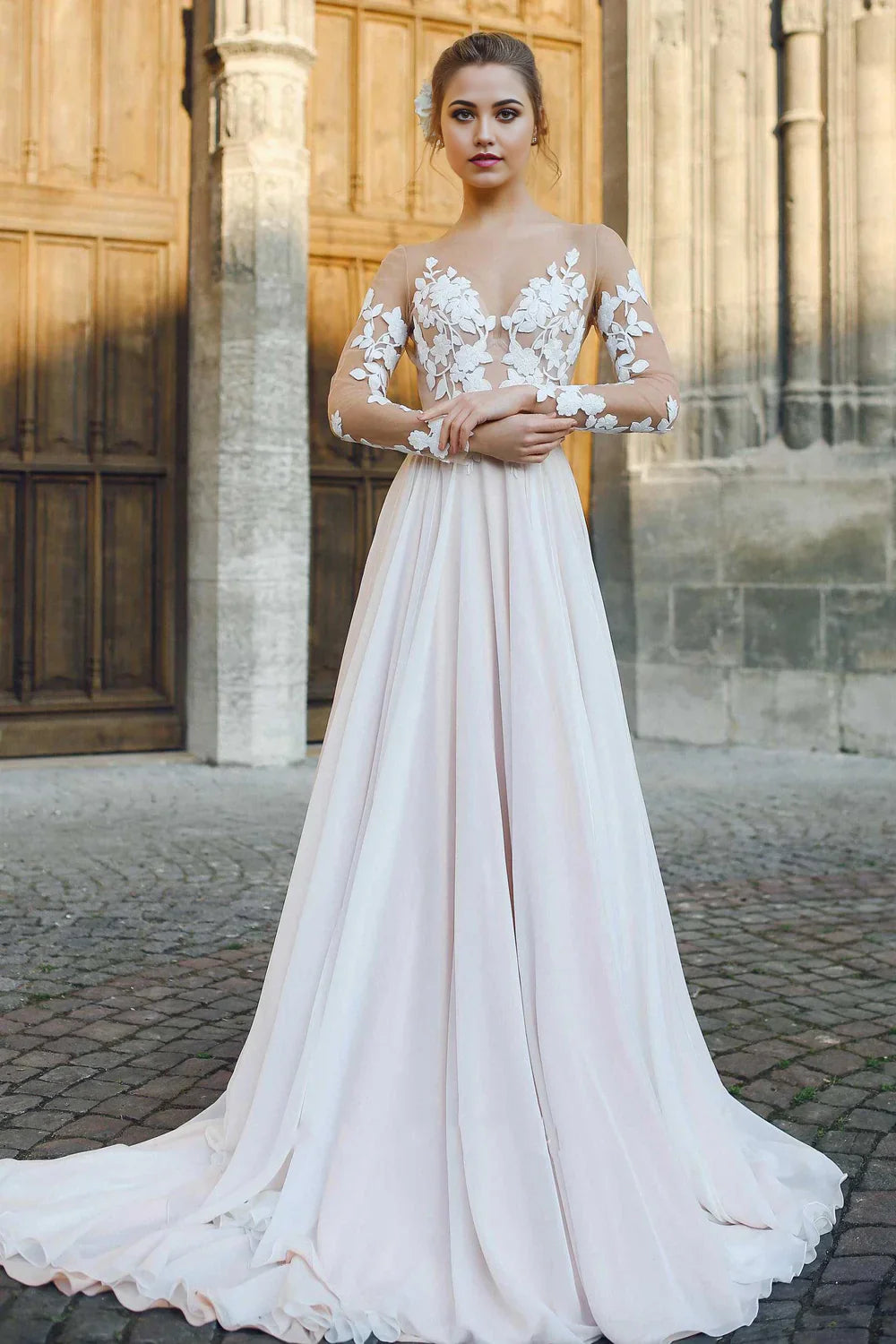 Bride wearing an elegant A-line chiffon wedding dress with appliqued details and long illusion sleeves.
