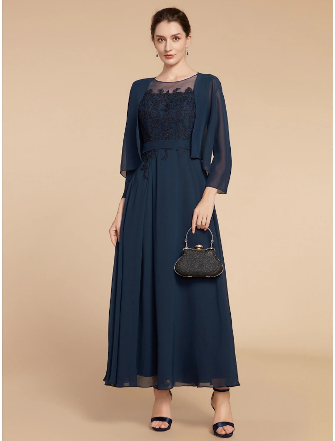 Woman wearing an elegant A-line navy blue Mother of the Bride dress with long sleeves and a jewel neck.