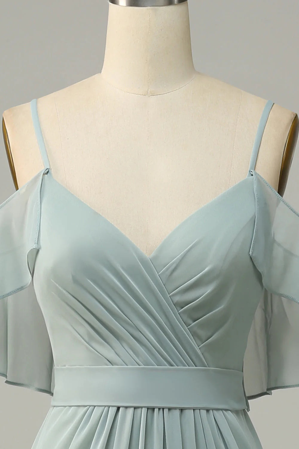 Close-up of the cold shoulder detail on a long bridesmaid dress, in a sage green hue.