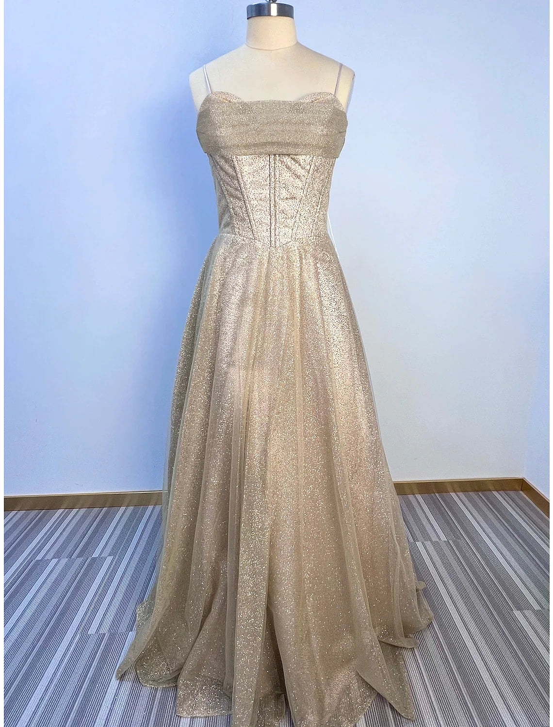 Woman wearing a shimmering A-line cowl neck glitter tulle evening gown.