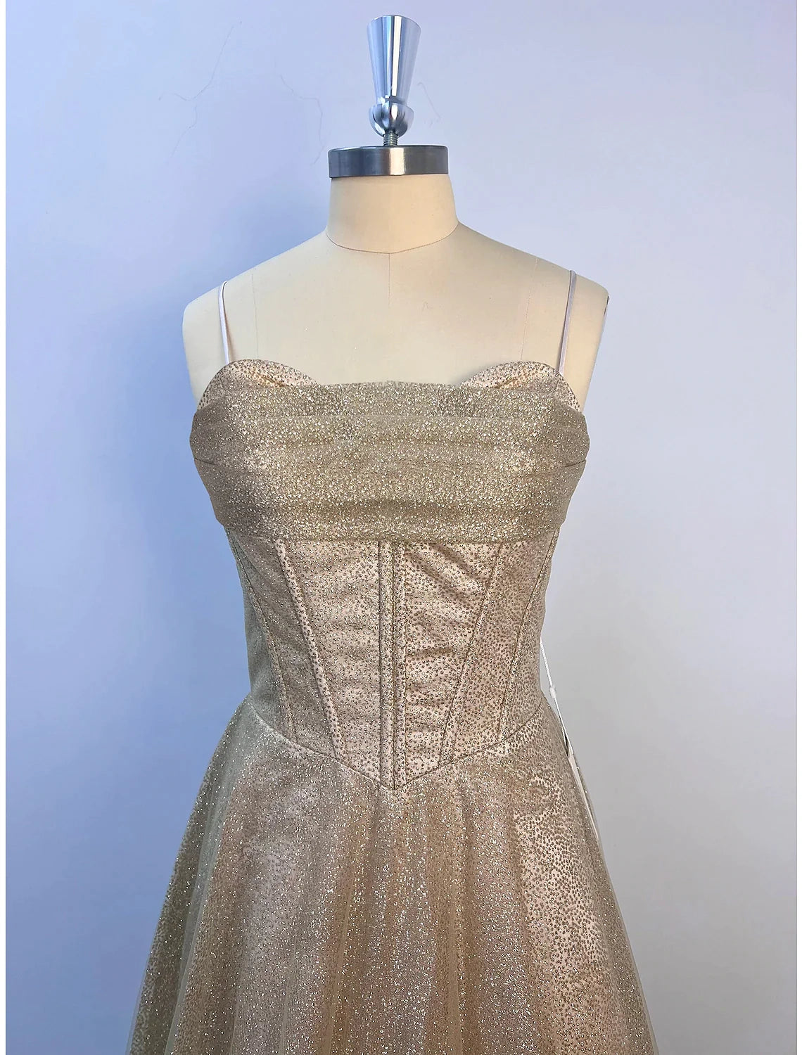 Side profile of a woman in a sleeveless cowl neck glitter evening dress.