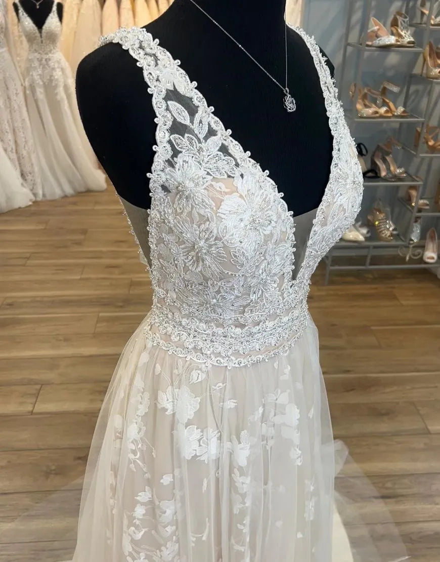 Elegant champagne bridal dress featuring a deep V-neckline and flowing A-line skirt.