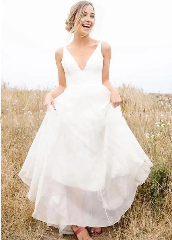 Front view of an elegant A-line deep V-neck sleeveless chiffon long beach wedding dress on a model.