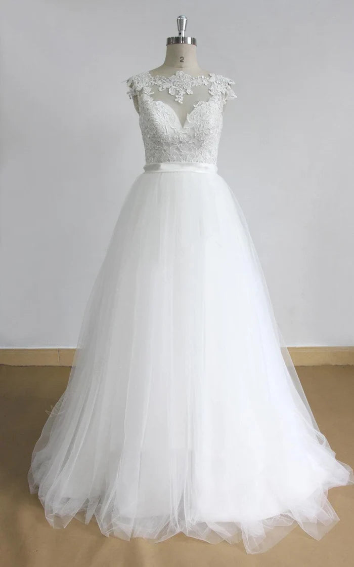 Model wearing an A-line lace tulle wedding dress with a deep V-neck.