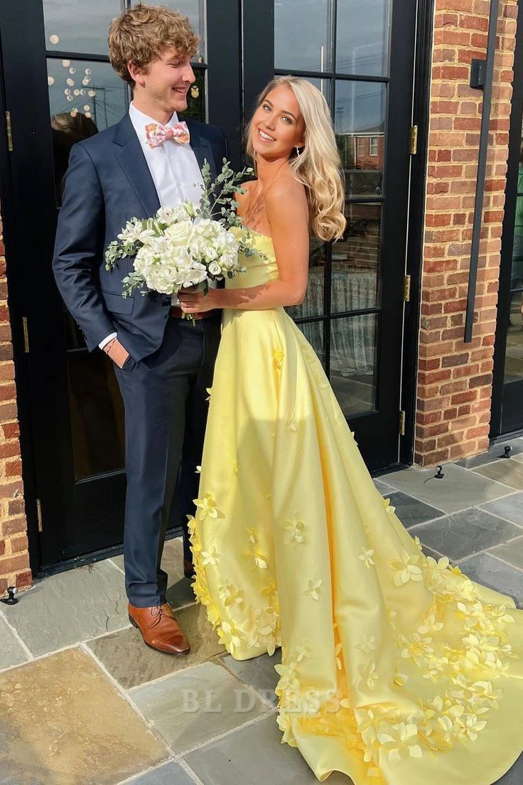 Yellow A-line empire-waist strapless satin gown with appliques.