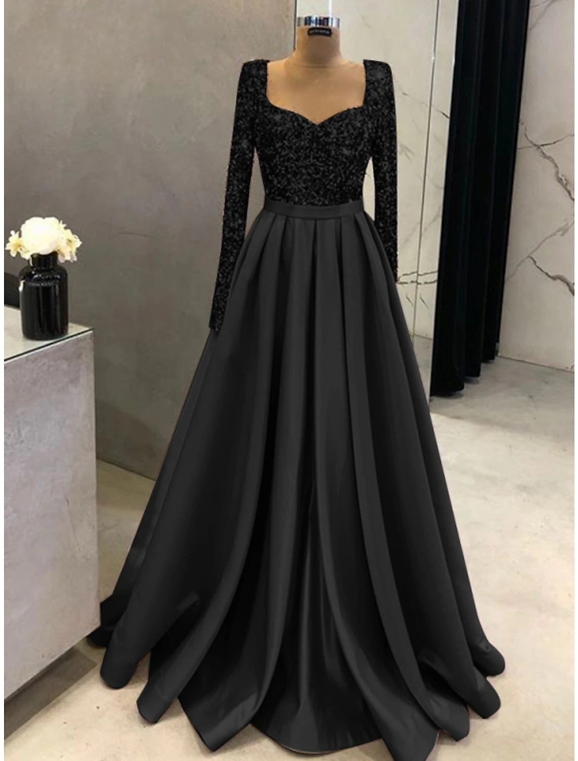 Close-up of the square neckline and long sleeve detail on the gown.