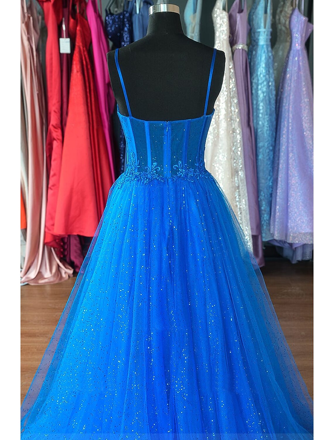 Back view of an A-Line glitter tulle prom dress with spaghetti straps and backless design.