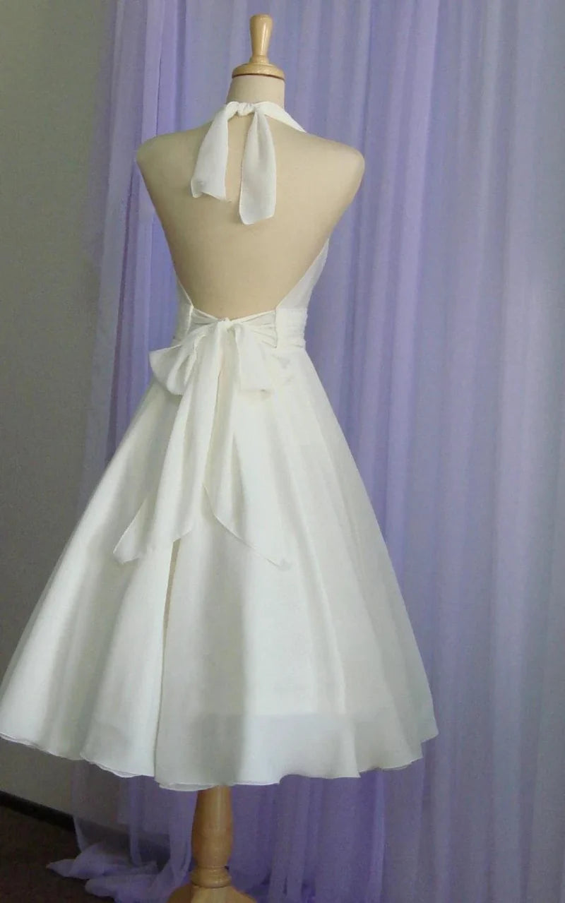 Elegant tea-length chiffon wedding dress, side view, showing halter neck and bow.