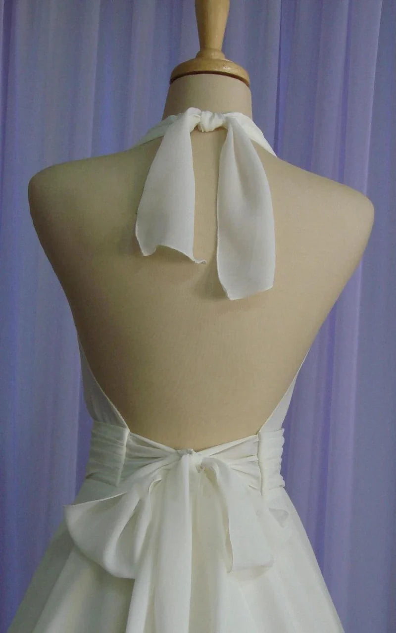 Back view of tea-length chiffon wedding dress featuring a delicate bow.