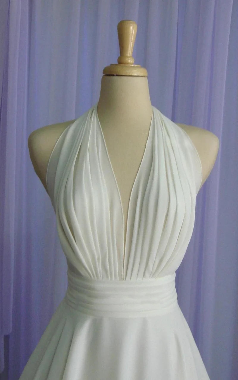 Full length view of a tea-length chiffon wedding dress with halter neckline.