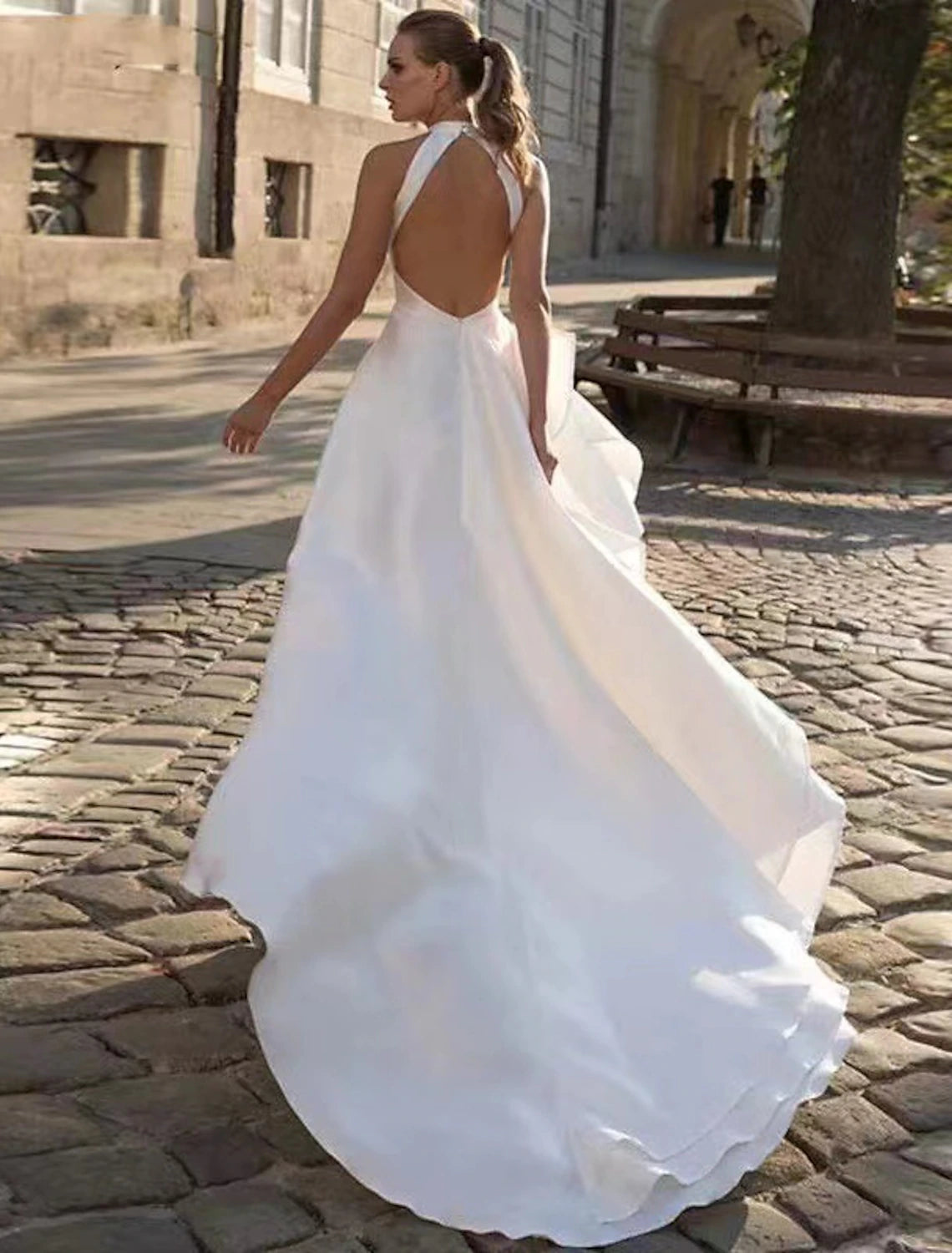 Back view of the white A-line halter wedding dress, highlighting the open back design and long court train.