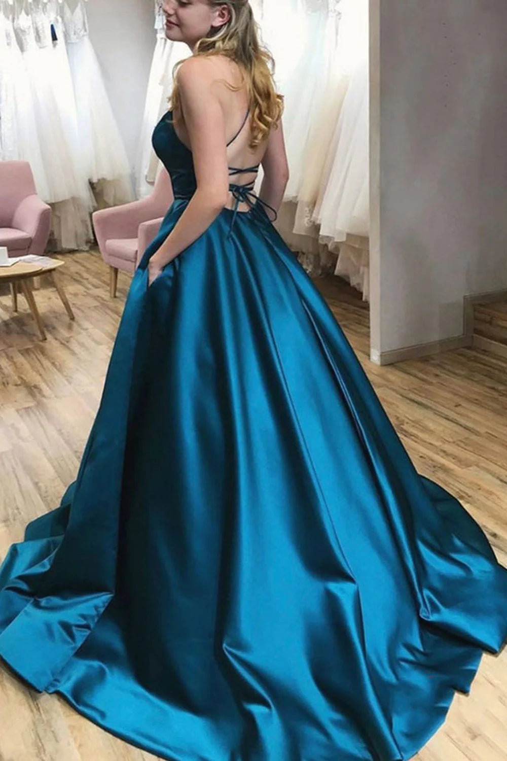 Model wearing a peacock blue A-line halter satin long prom dress.