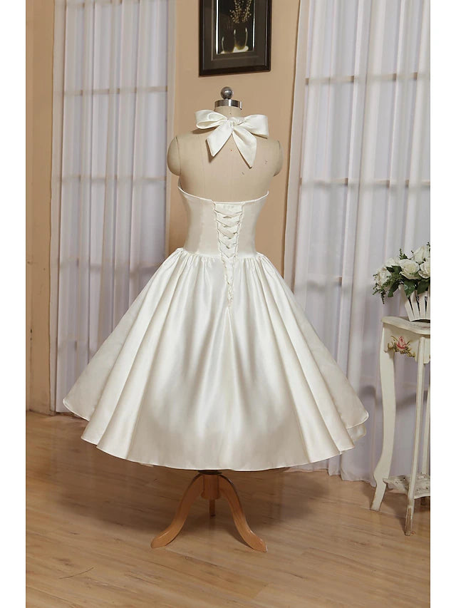 Close-up of the white satin fabric and pleats on the A-line tea-length dress.