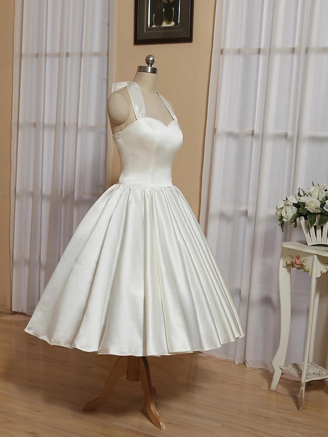 Detail of the halter neckline and bow on the white satin bridal shower dress.