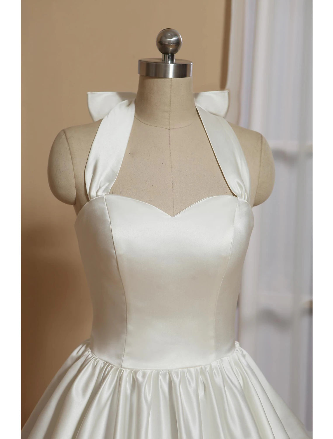 Side view of white A-line halter tea length satin wedding dress.