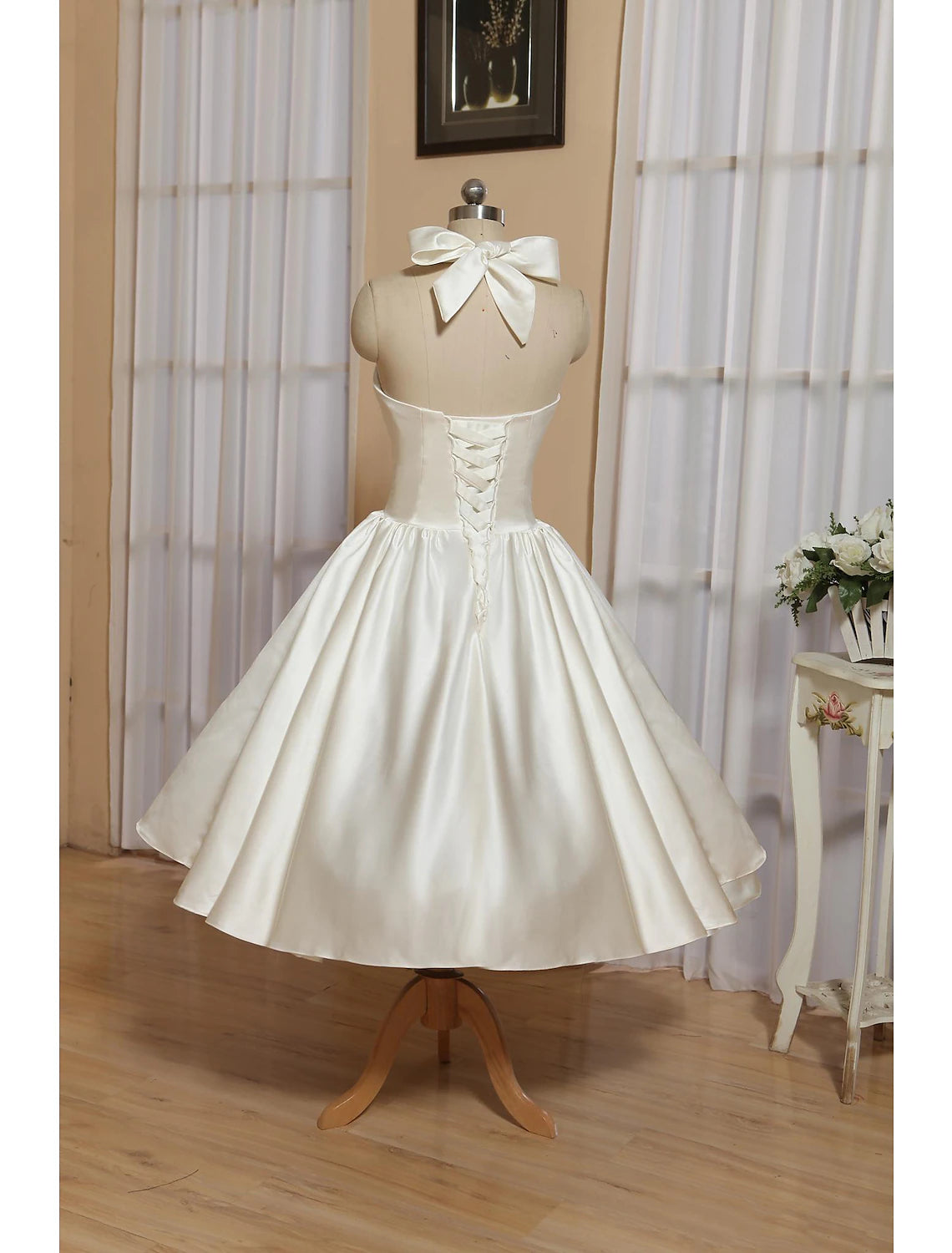 Close-up of bow and pleat details on white satin wedding dress.
