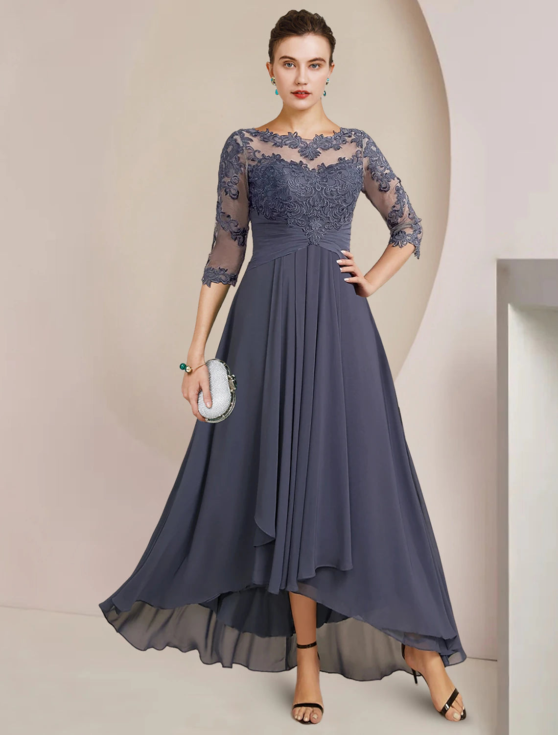 Woman wearing an elegant A-line high-low tea length mother of the bride dress with 3/4 sleeves and lace details.