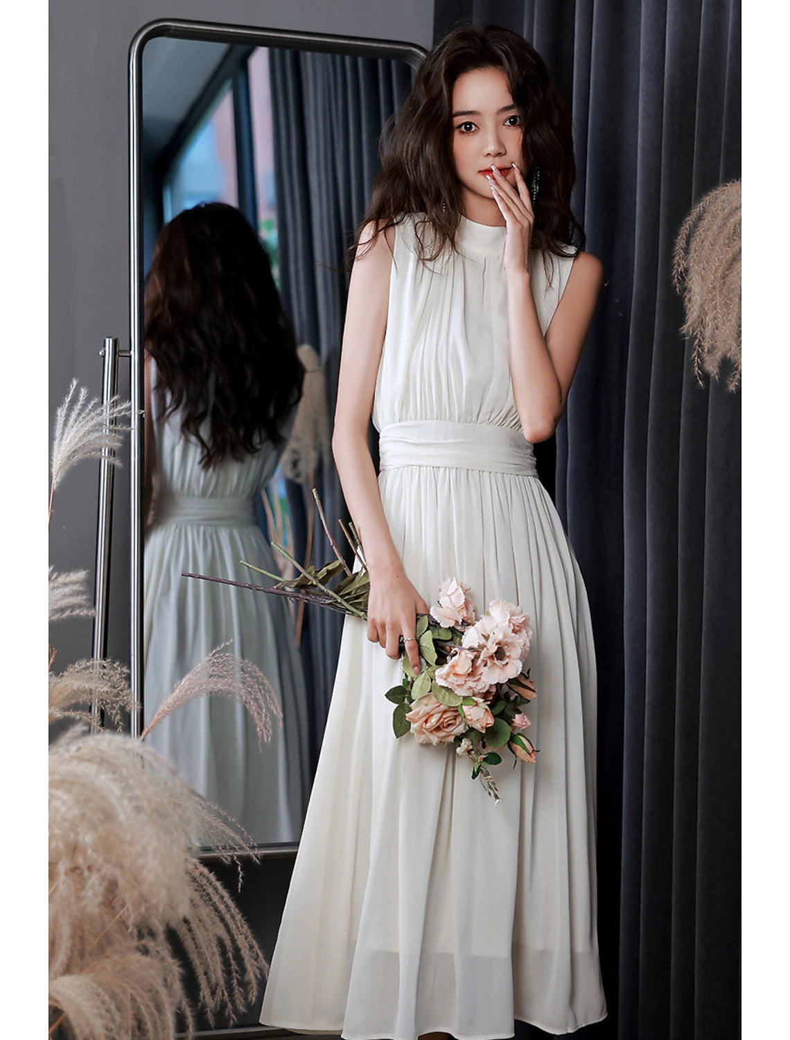 Model wearing a white A-line high neck sleeveless tea length chiffon reception dress.
