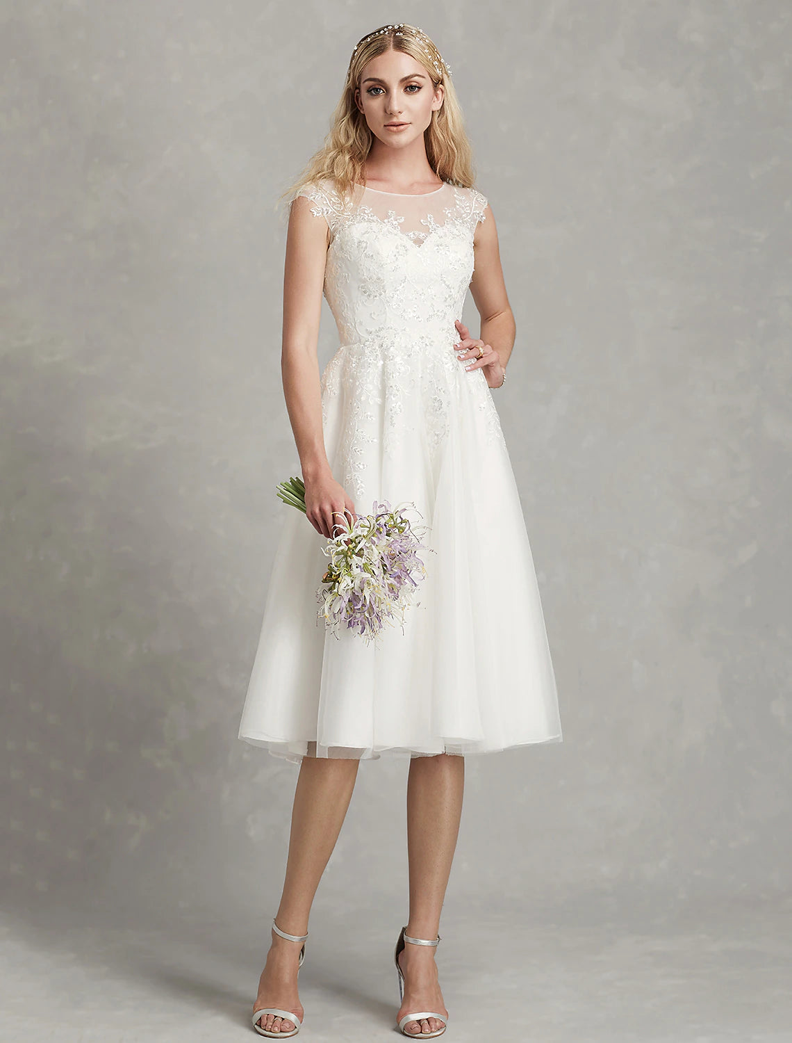 Side view of a white A-line reception dress, highlighting the knee-length hem and lace details.