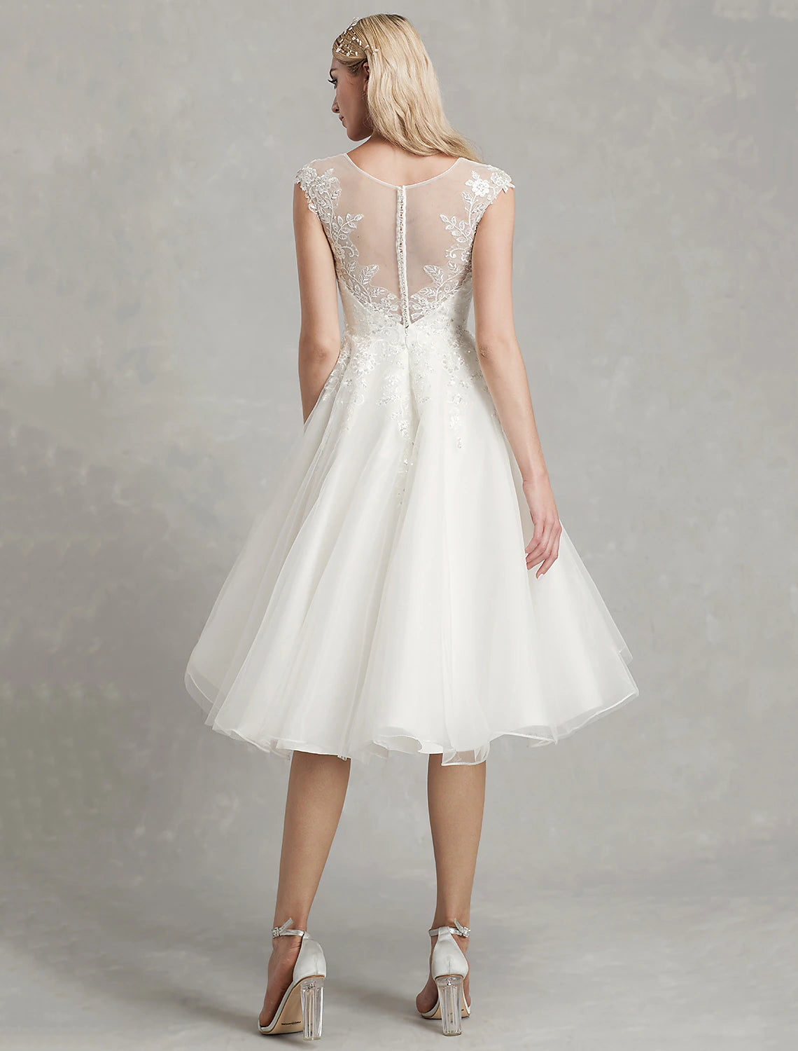 Close-up of the illusion neckline and cap sleeves on a white bridal gown.