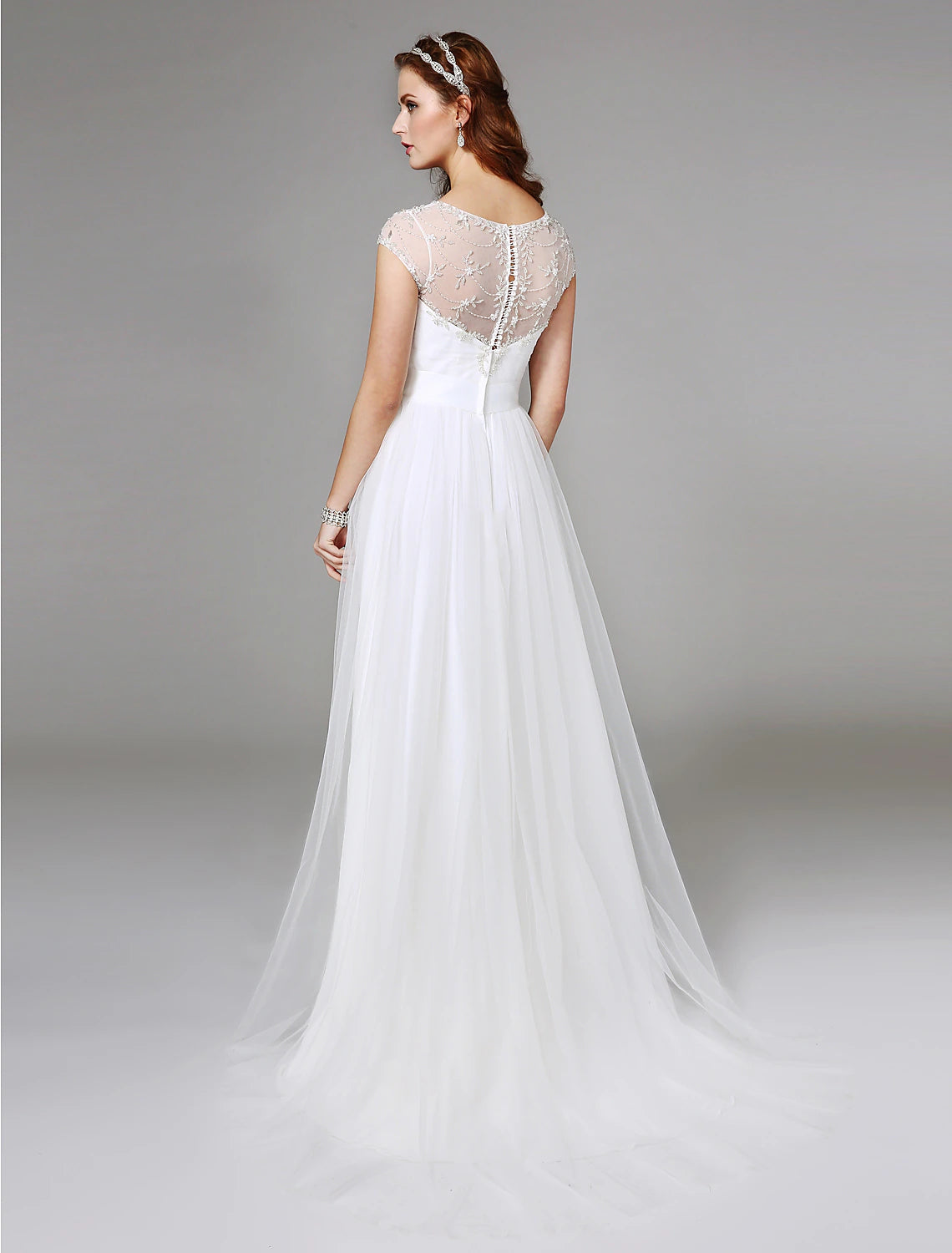 Side view of the A-line wedding dress, showcasing the sweep train and delicate lace details.