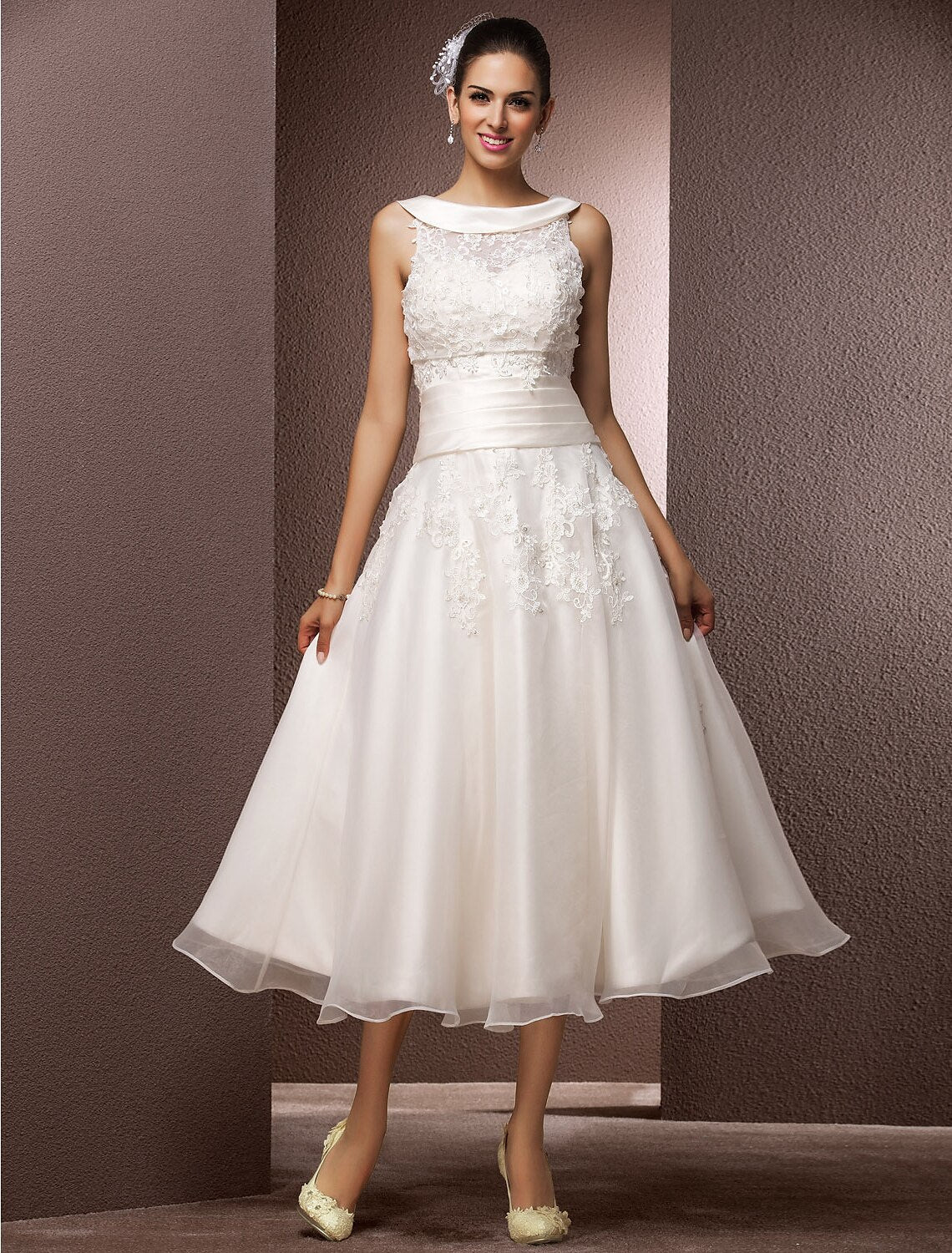 Front view of the A-line tea length wedding dress with illusion neck, lace, and pearl beading.
