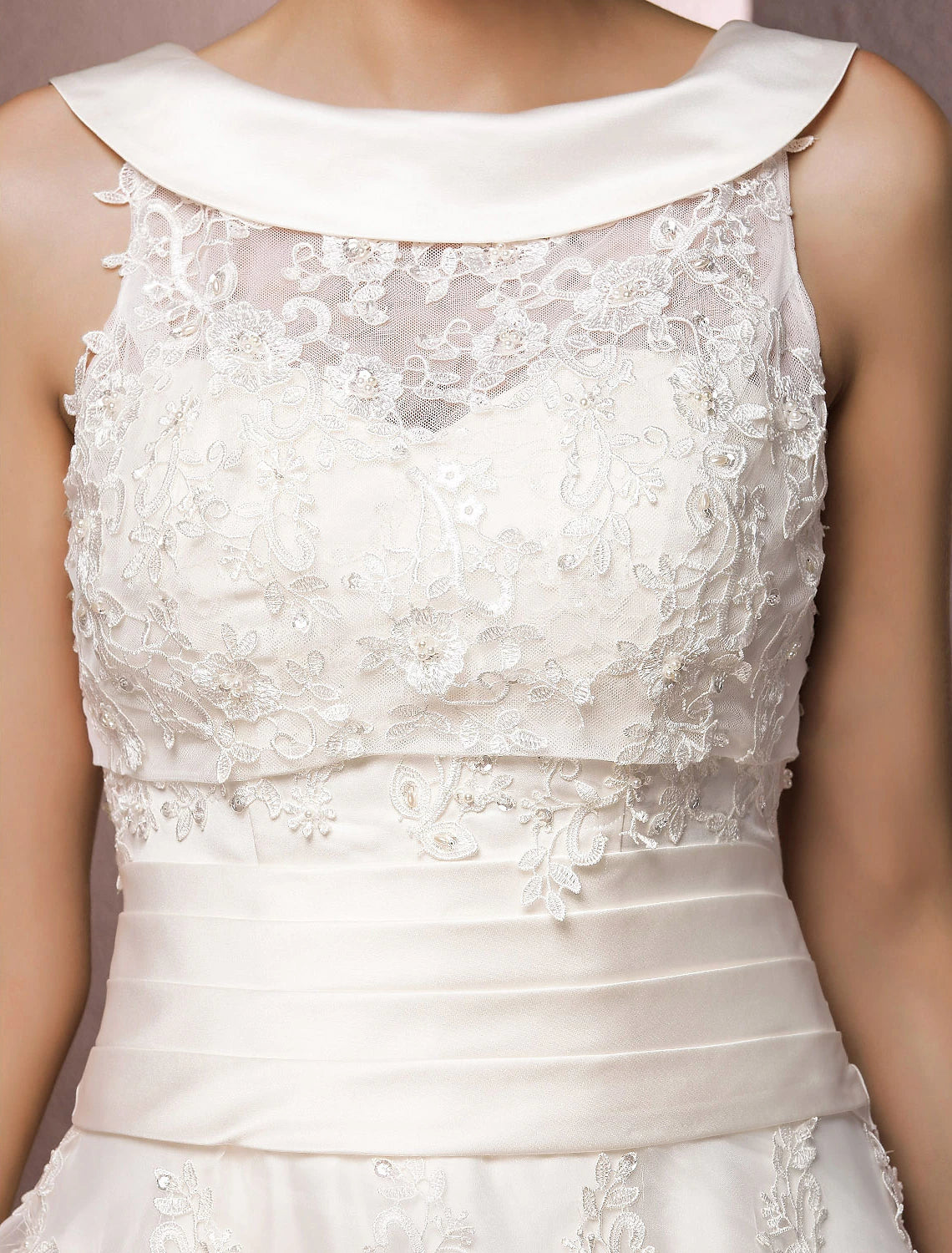 Detailed view of the lace and pearl embellishments on the sleeveless wedding dress.