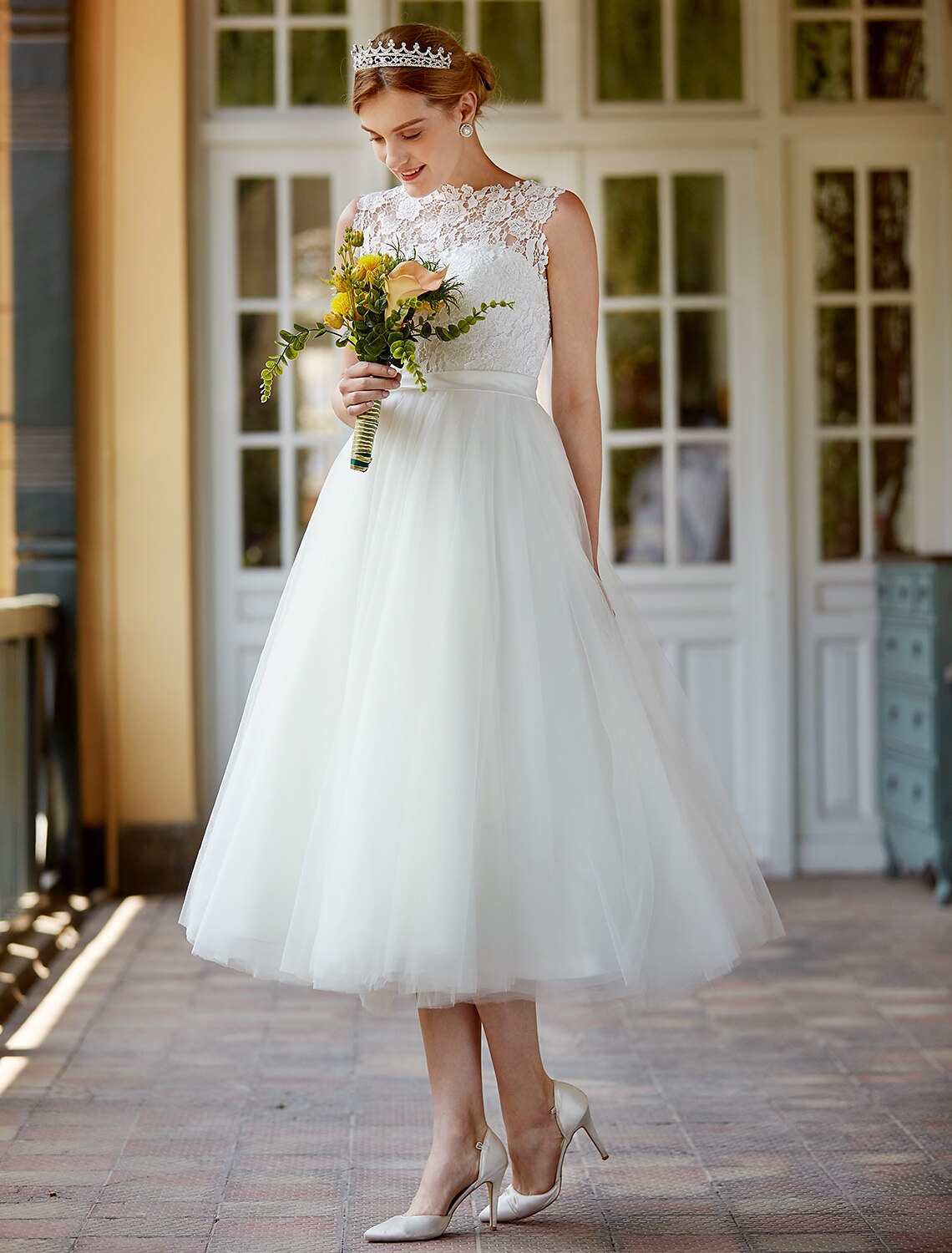 Close-up of the lace detail and illusion neckline on a white wedding reception dress.