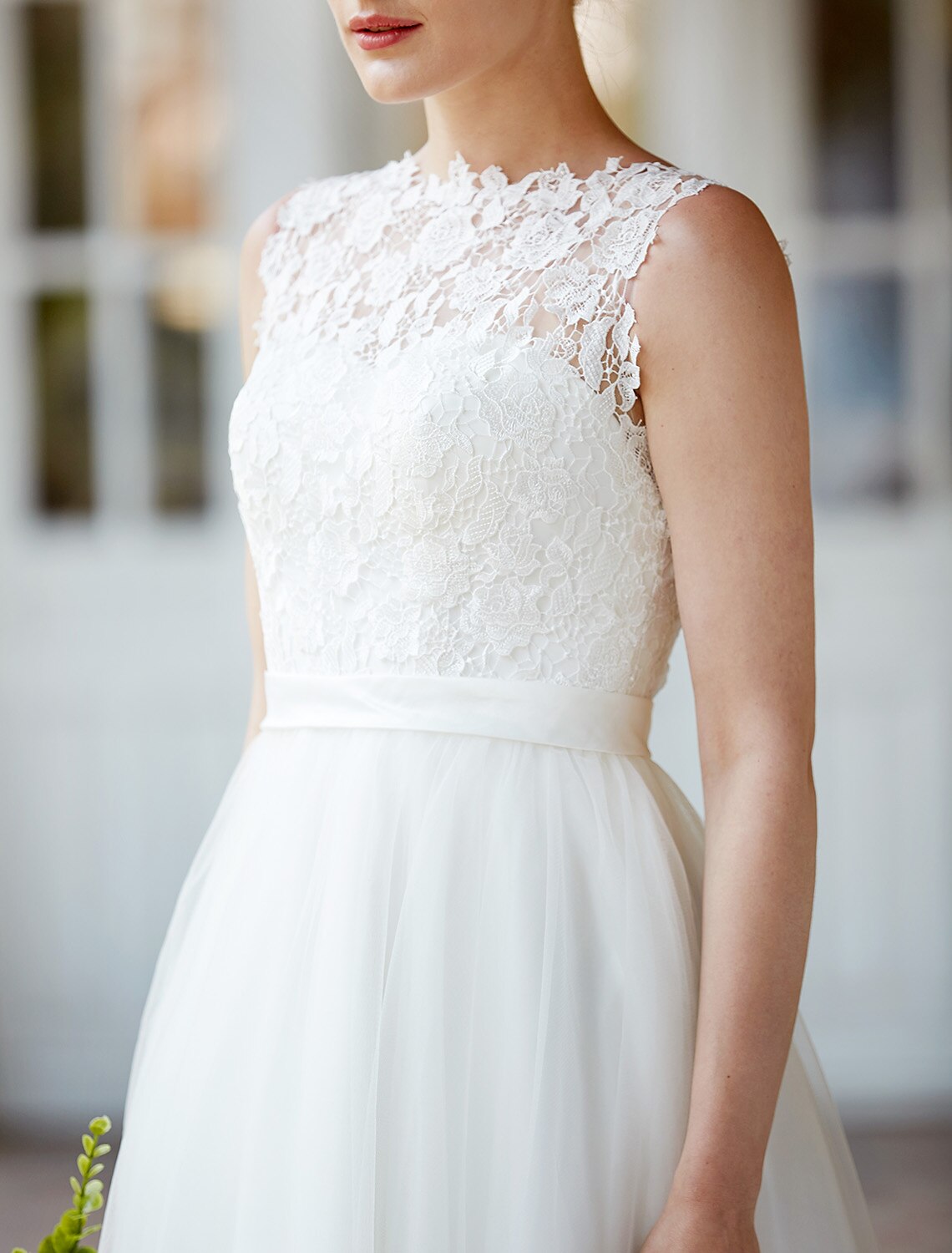 Detail of the sash and buttons on the back of a white A-line wedding dress.