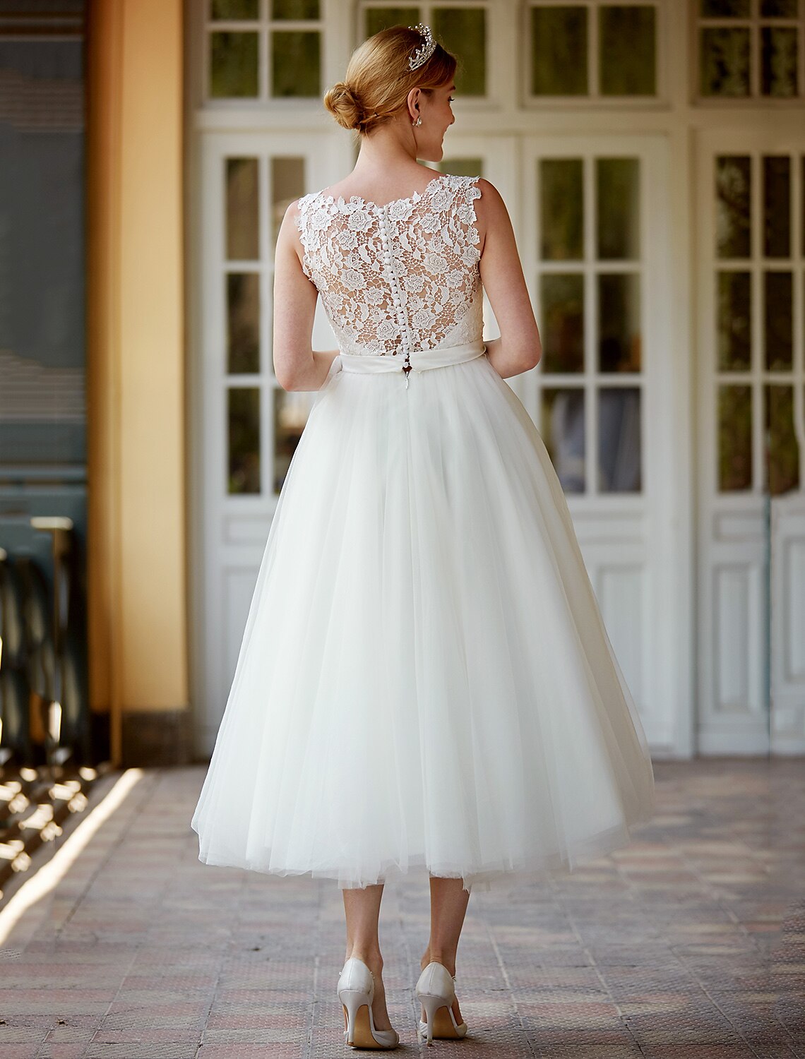 Elegant white A-line tea length dress with illusion neckline and lace overlay.