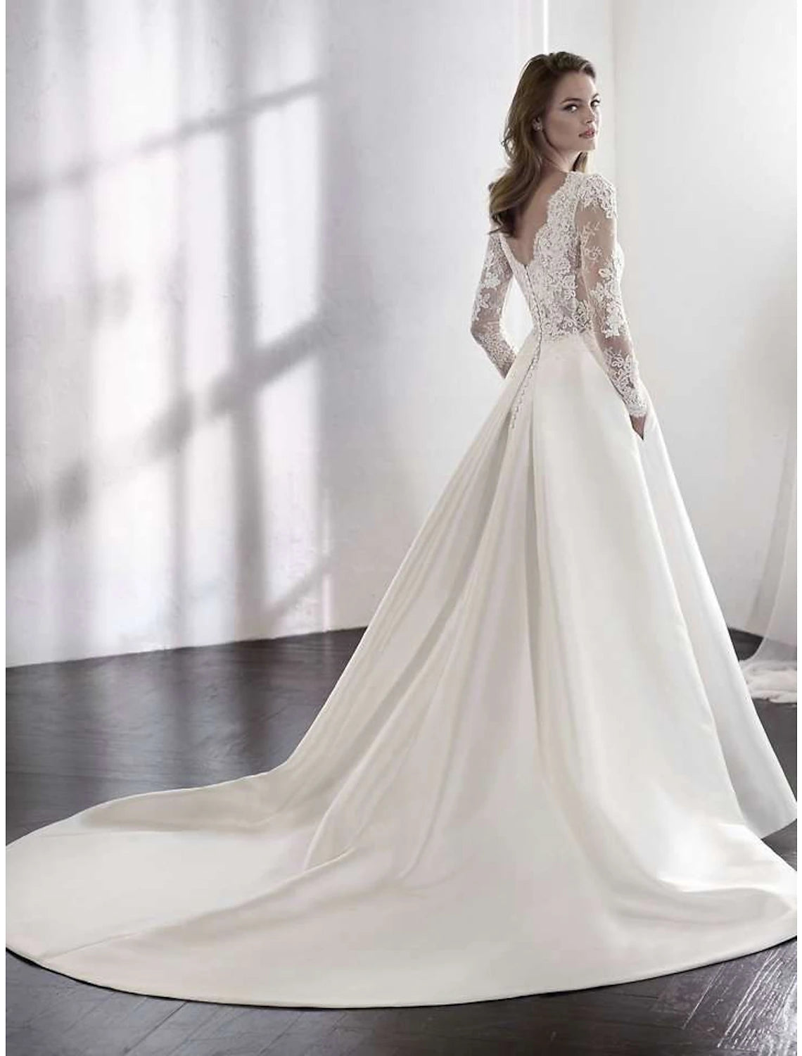 Back view of the A-Line satin wedding gown showcasing the chapel train and lace pleats.