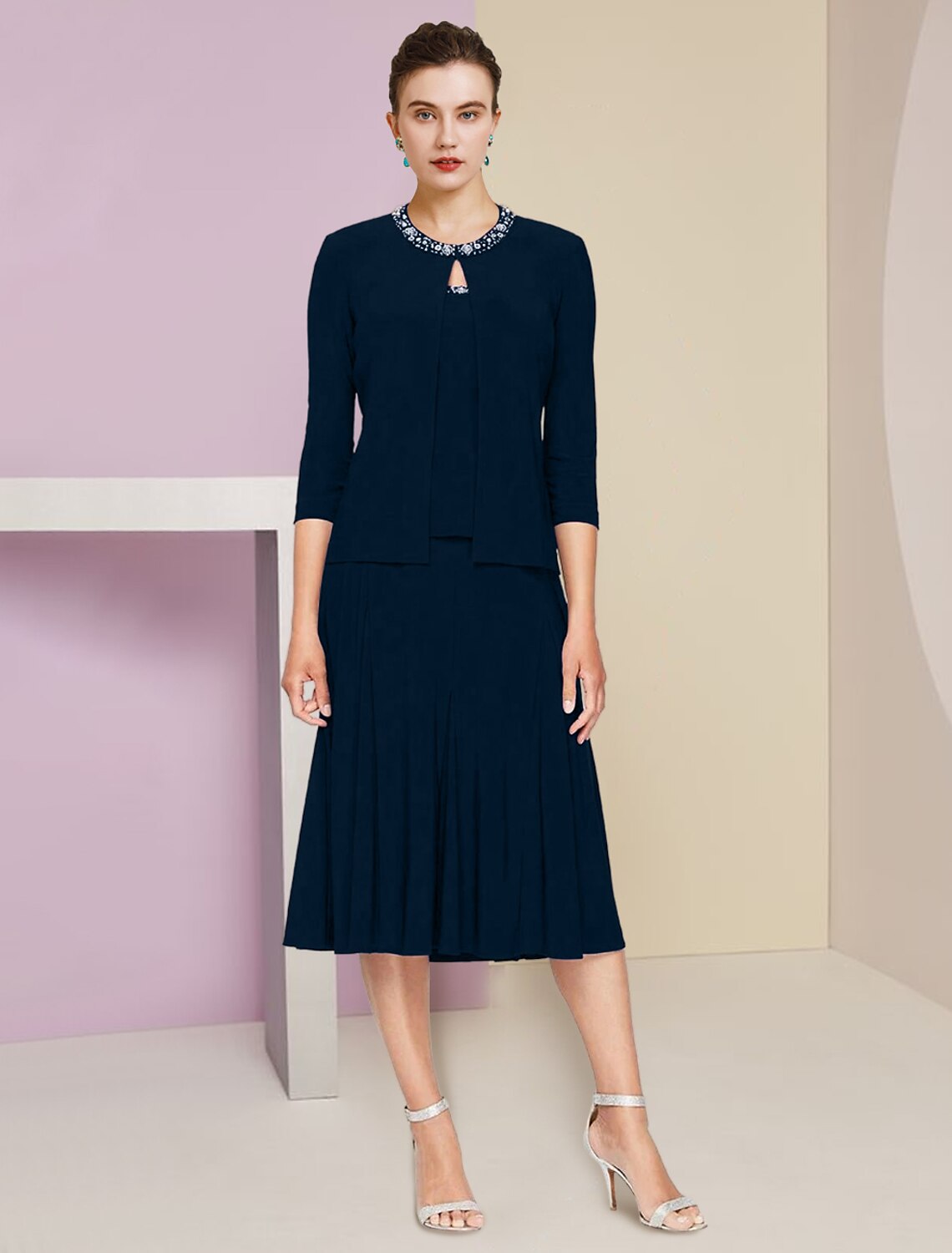 Elegant A-line knee-length dress with jewel neck and 3/4 sleeves, featuring pleats and crystal embellishments.