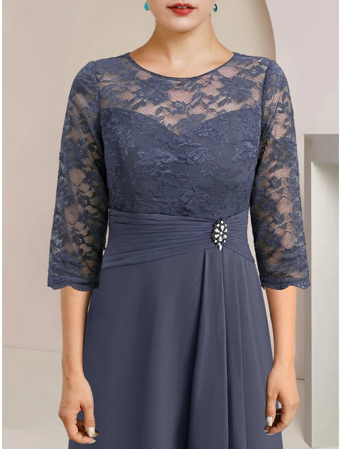 Close-up of the dress bodice, highlighting lace details and crystal brooch.
