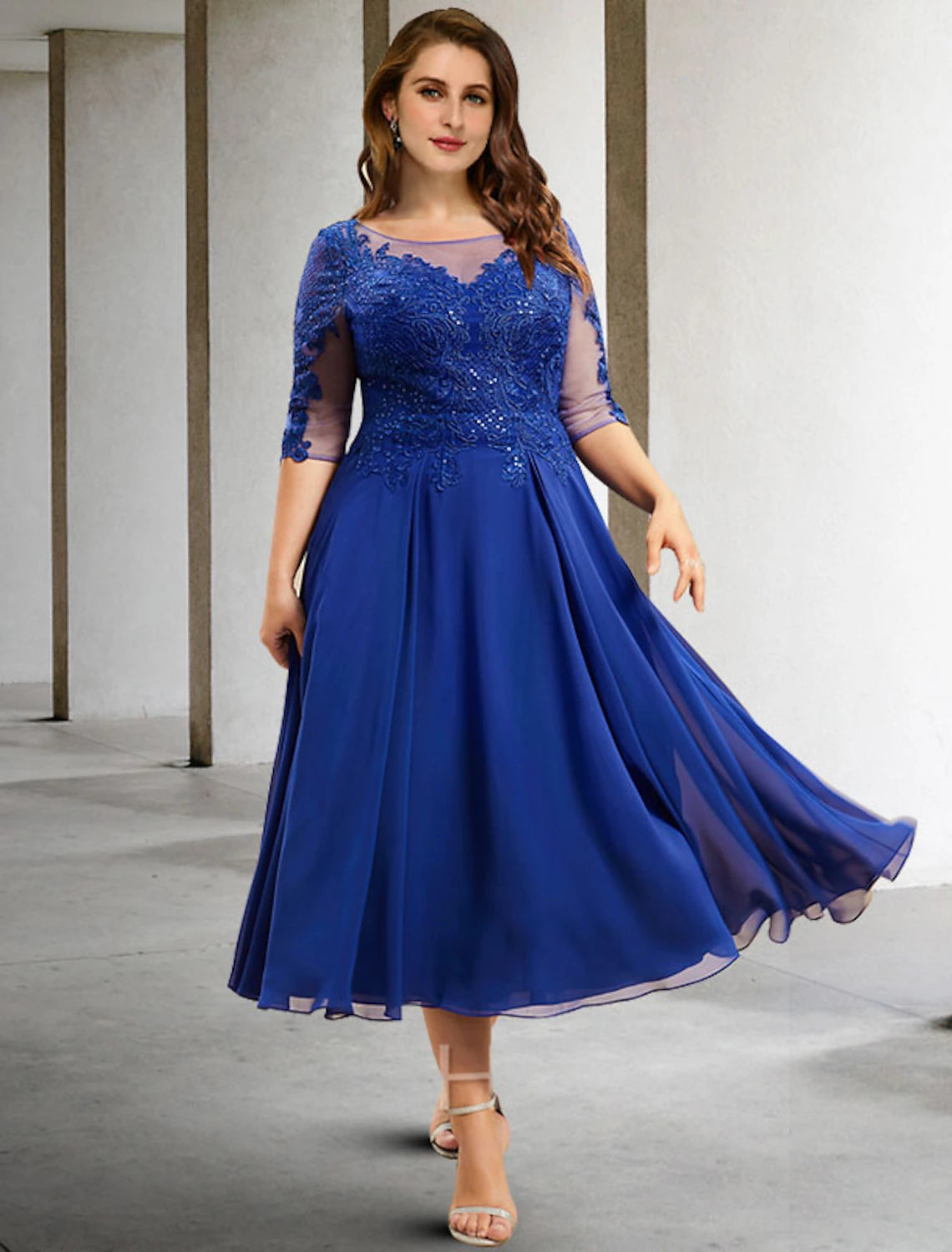 Woman in an elegant A-line tea-length Mother of the Bride dress with half sleeves.
