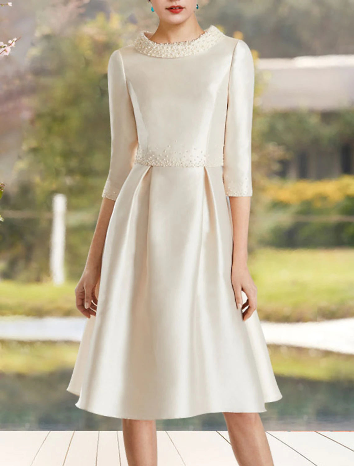 Side view of the knee-length satin Mother of the Bride dress with beading.