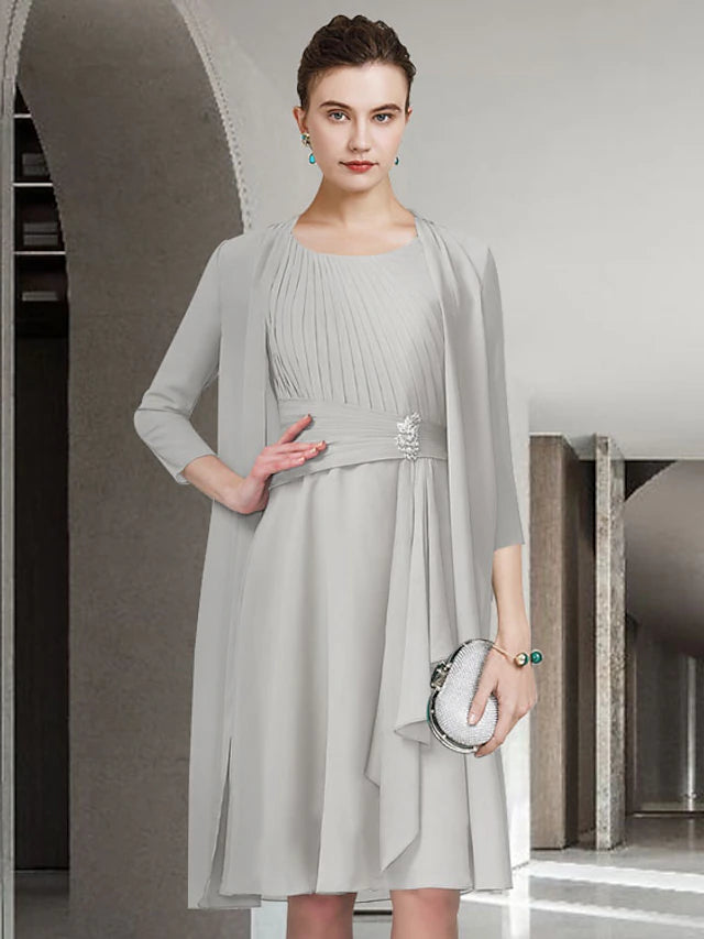Woman in elegant blue A-line two-piece dress, jewel neck, knee-length, front view.