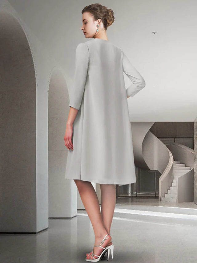 Woman in blue A-line two-piece dress, jewel neck, knee-length, back view.