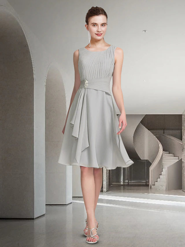 Woman in blue A-line two-piece dress, jewel neck, knee-length, close-up of pleated bodice.