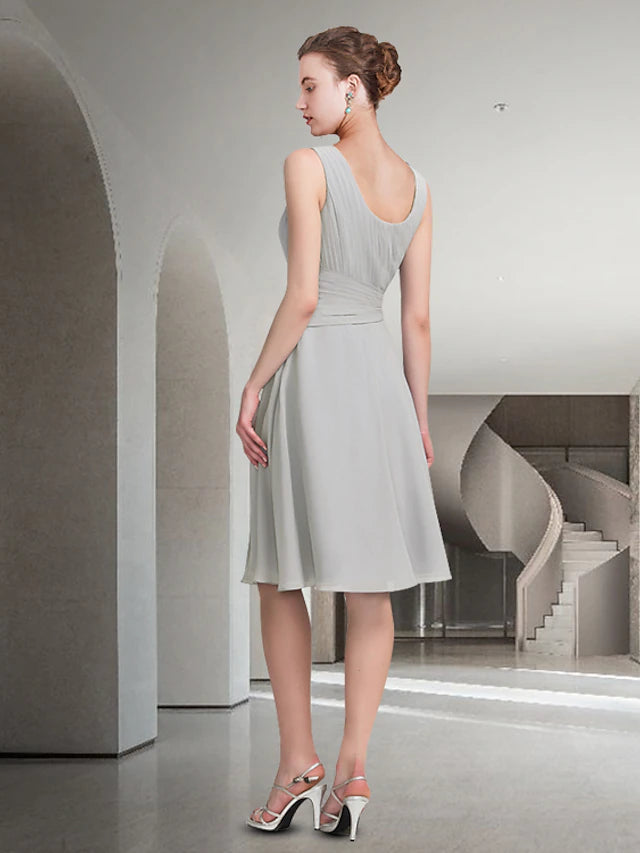Woman in blue A-line two-piece dress, jewel neck, knee-length, seated pose.